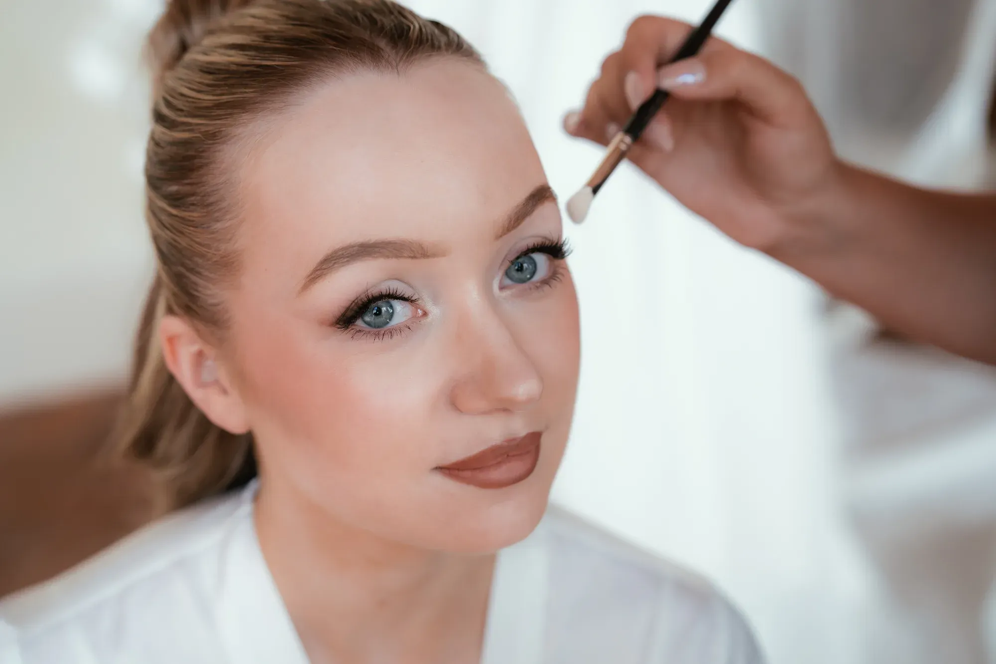 Bridal makeup in progress: a brush on the closed eye